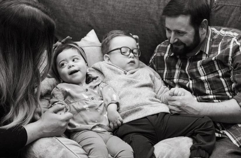 Black-and-white photograph of a family on the couch, parents holding their two children close